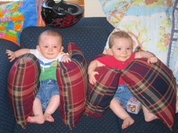 Twins on couch propped by pillows